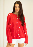 Woman wearing a red cardigan with white star patterns on a plain background