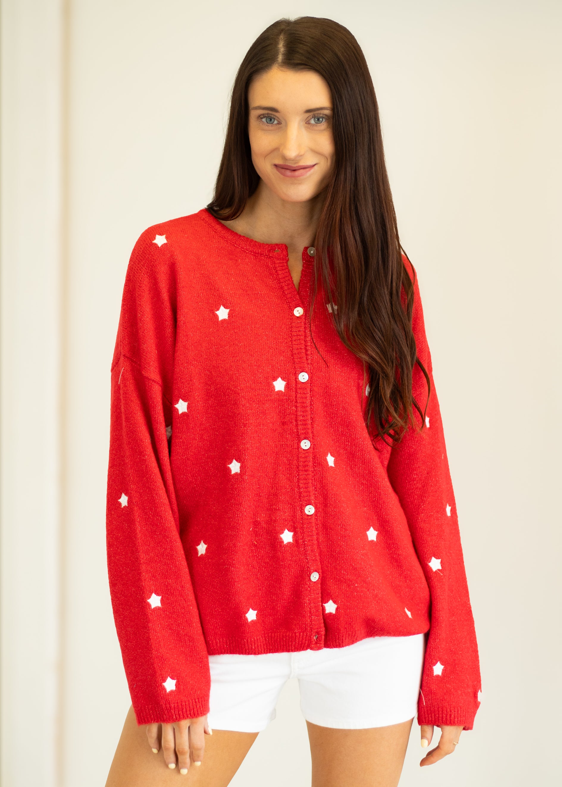 Woman wearing a red cardigan with white star patterns on a plain background