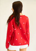 Person wearing a red sweater with white star patterns on a plain background