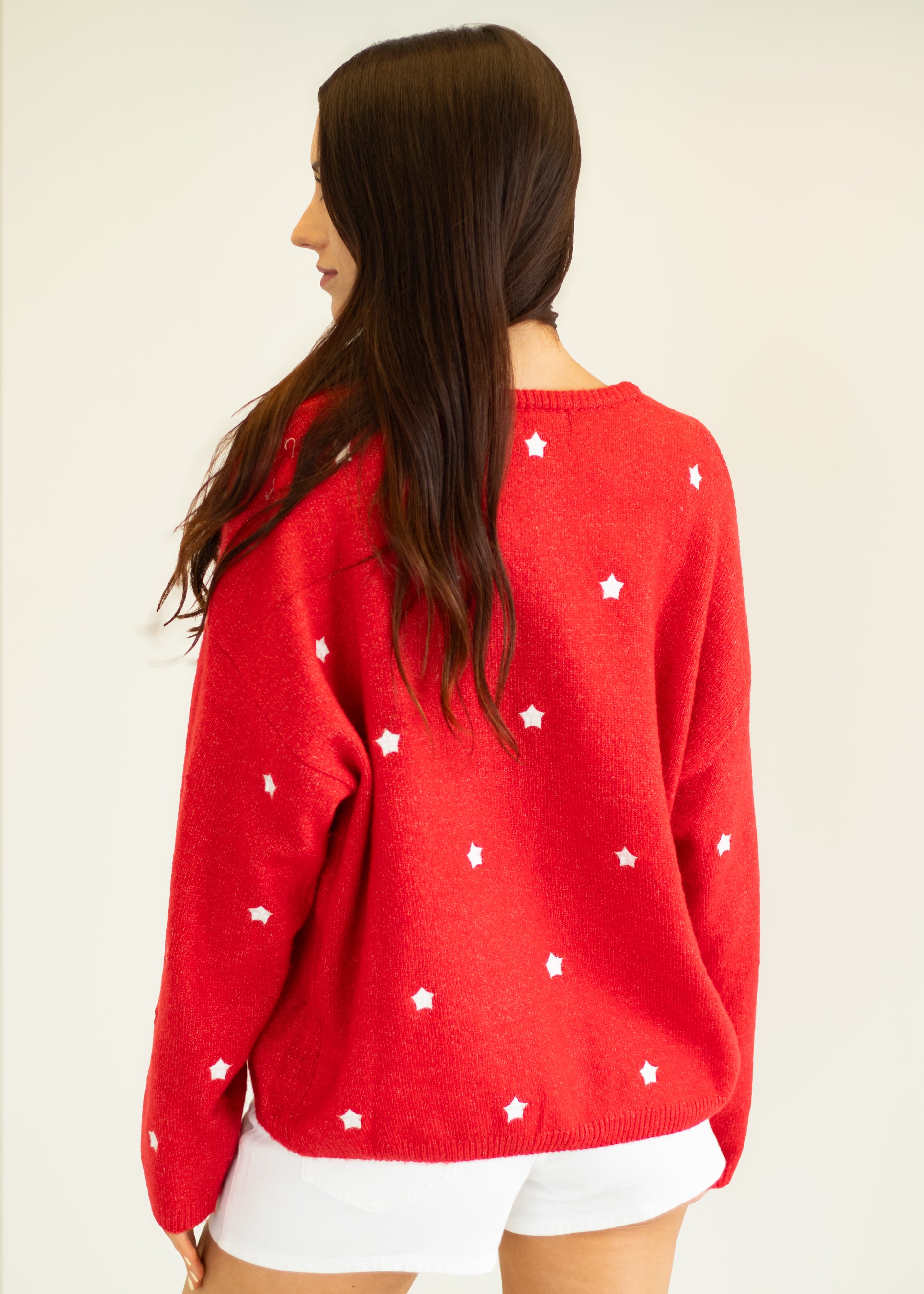 Person wearing a red sweater with white star patterns on a plain background