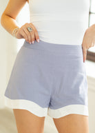 Light purple shorts with white trim worn by a person on a plain background