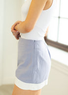 Light blue skirt with white trim worn by a person against a neutral background