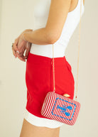 Person wearing a red skirt and holding a striped handbag with a blue anchor design.