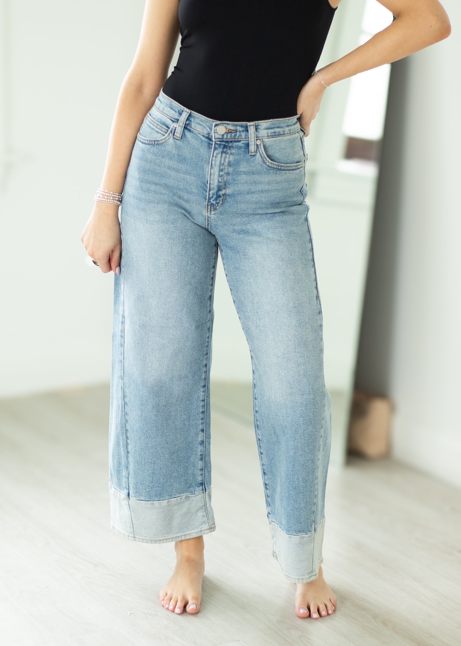 Person wearing light blue jeans and a black top in a minimalistic setting