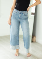 Person wearing light blue jeans and a black top in a minimalistic setting