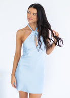 A woman modeling a light blue halter mini dress with a keyhole cutout at the chest, posed against a plain white studio background.