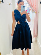 Woman taking a mirror selfie wearing a blue dress with a knot detail.