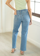 Person wearing light blue jeans and a light green top in a bright room.
