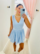 Woman taking a mirror selfie wearing a light blue dress indoors.