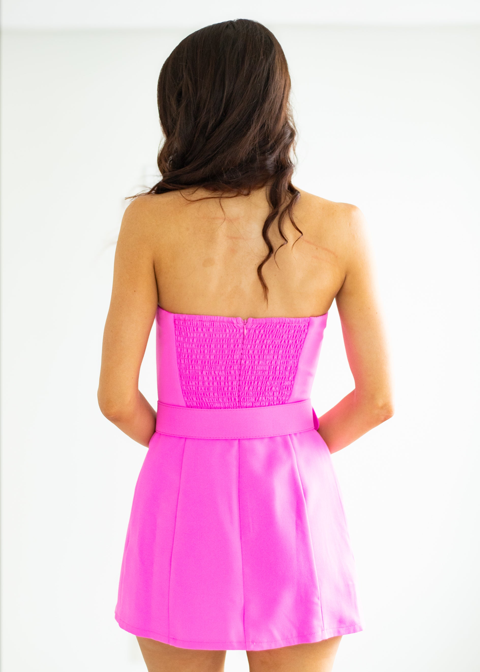 Pink strapless dress worn by a person on a white background