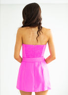 Pink strapless dress worn by a person on a white background