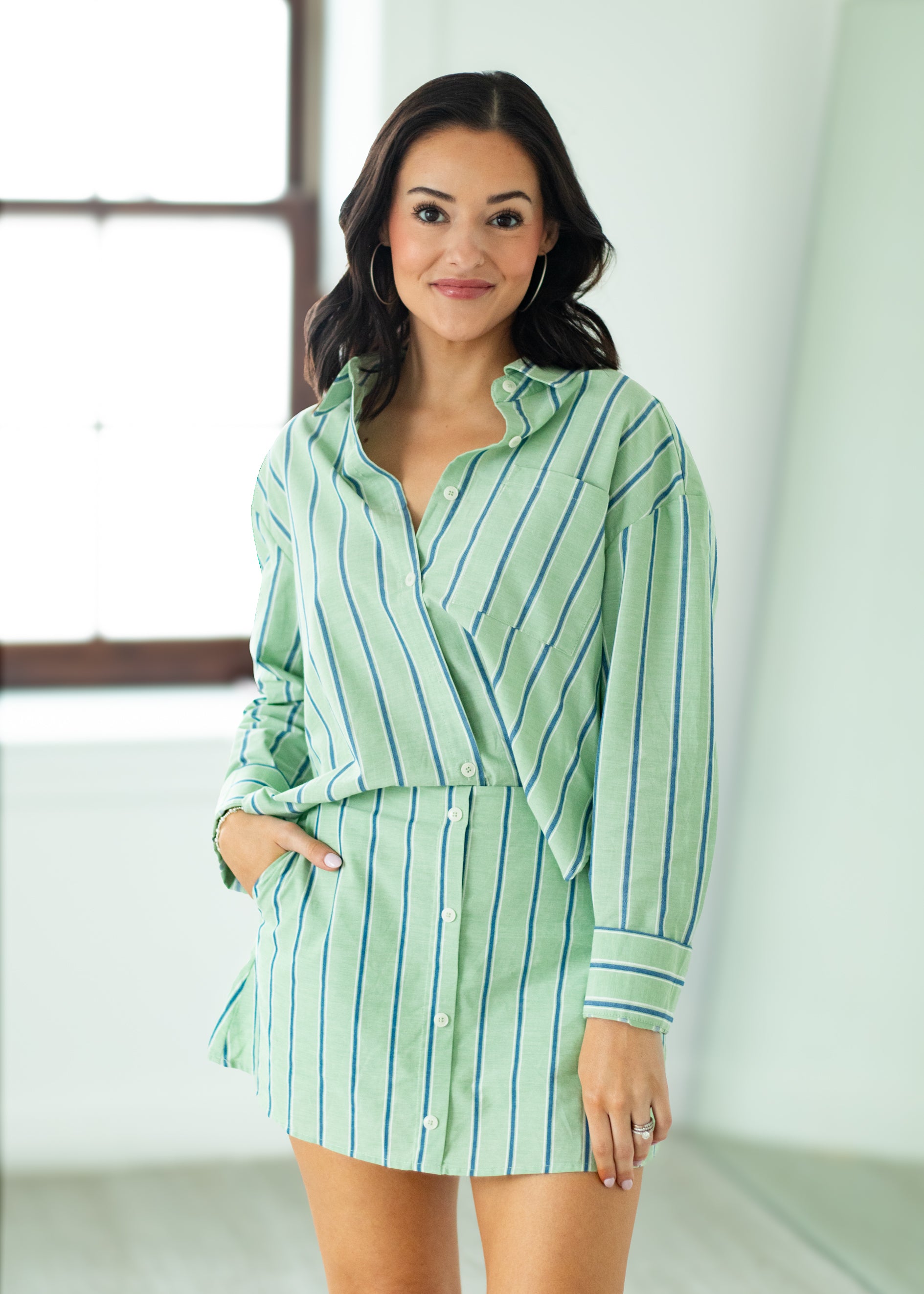 Woman wearing a green and white striped shirt and skirt in a bright room.