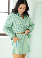 Woman wearing a green and white striped shirt and skirt in a bright room.