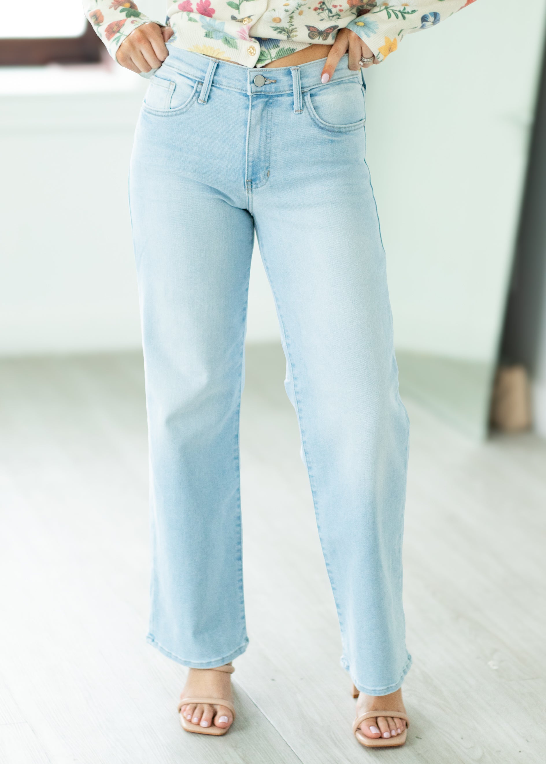 Light blue jeans worn by a person on a white floor.