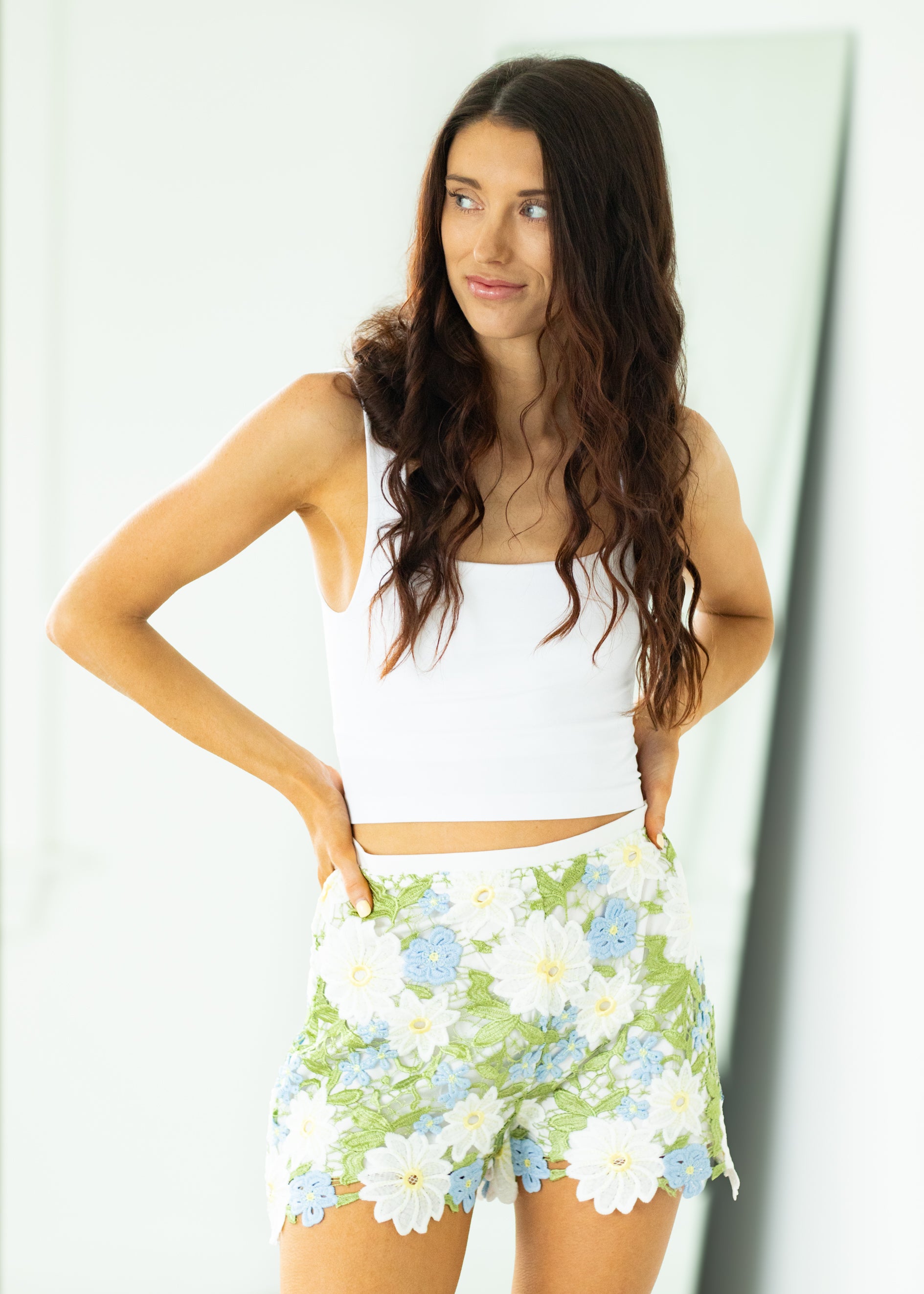Woman wearing a white top and floral skirt against a plain background