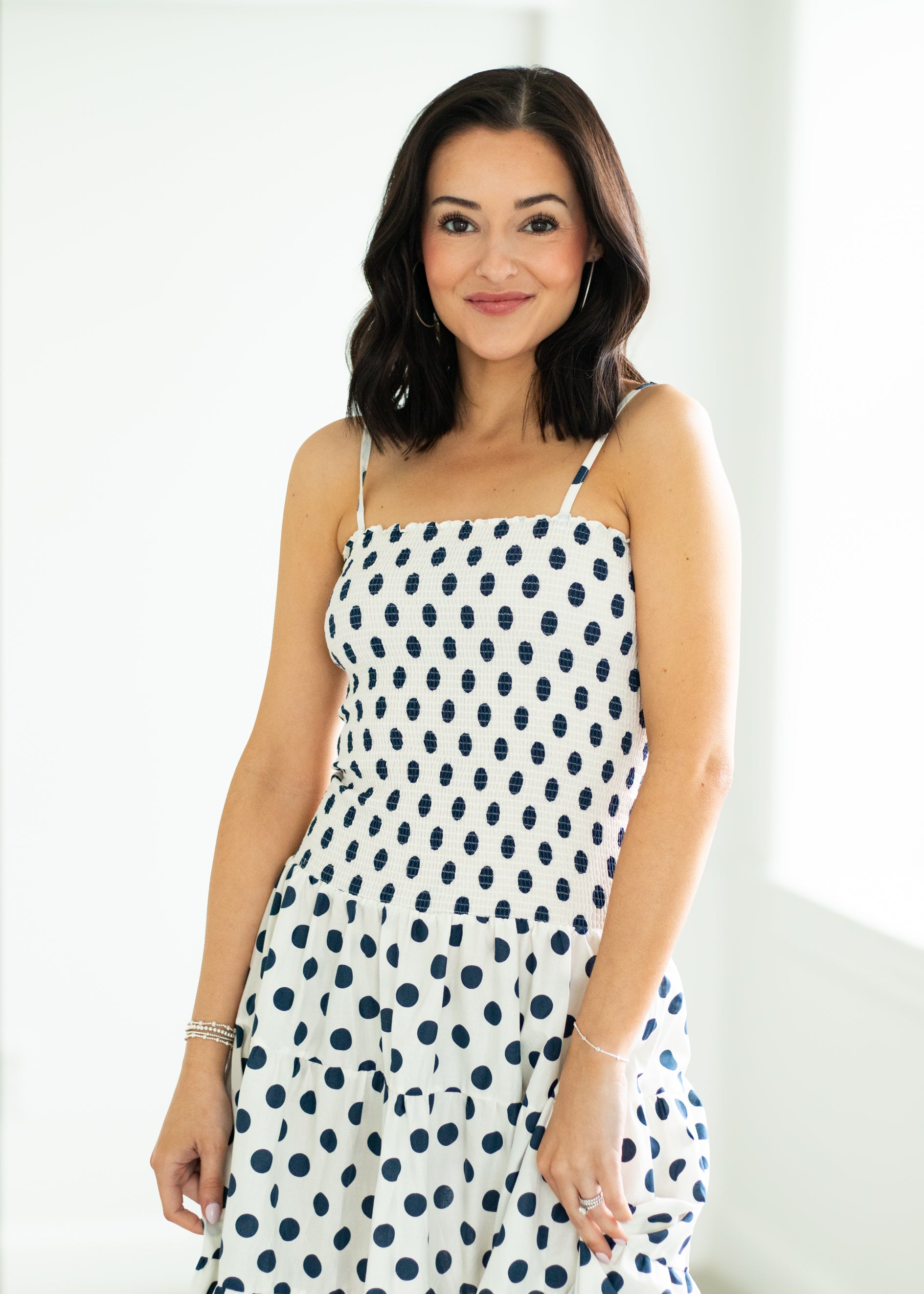 Woman wearing a white dress with blue polka dots against a white background