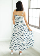 Woman wearing a polka dot dress standing in a bright room.