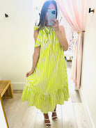 Person wearing a green and white striped dress in a room with light-colored walls and wooden floor.