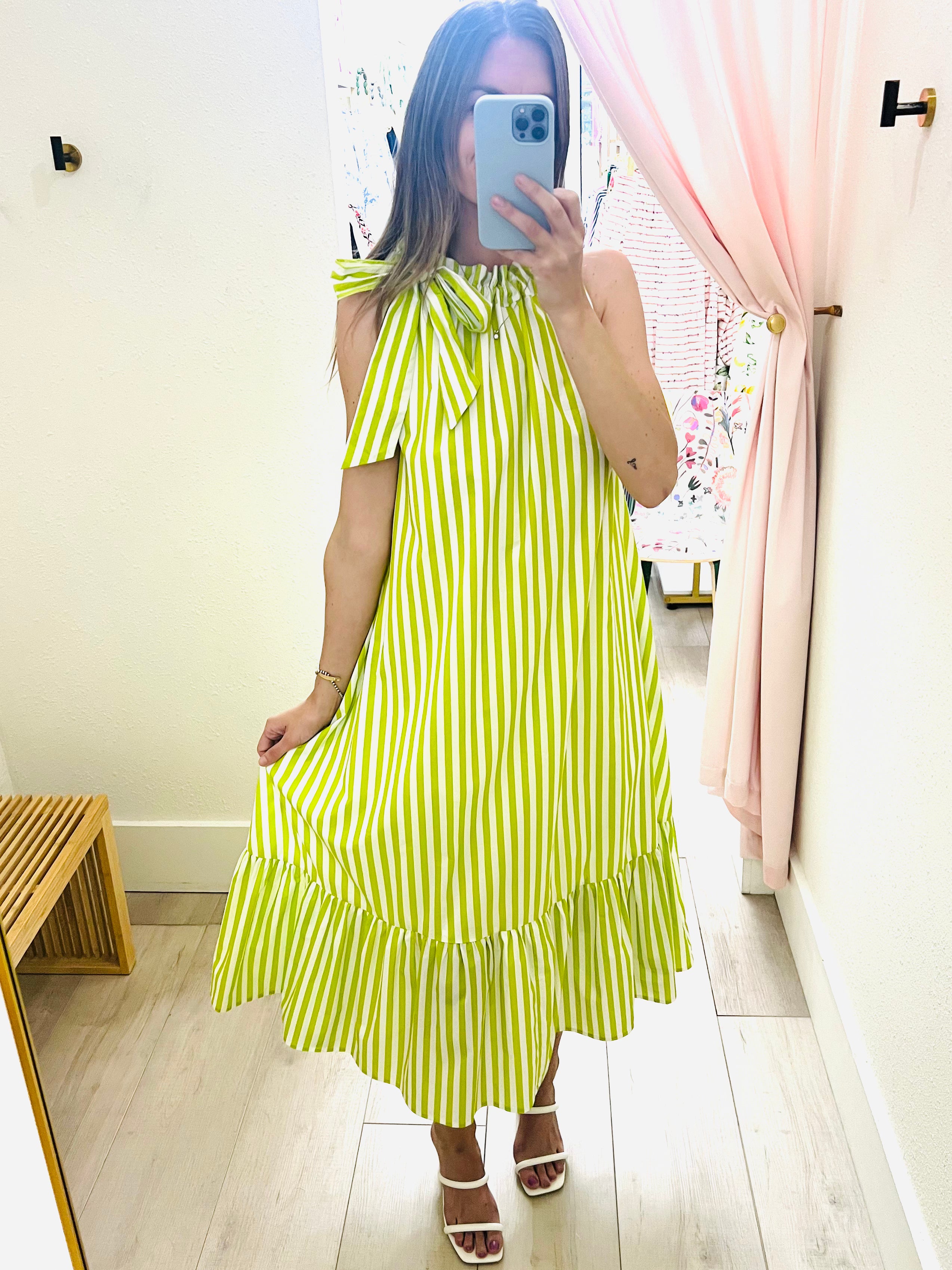 Person wearing a green and white striped dress in a room with light-colored walls and wooden floor.