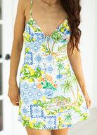 Woman wearing a colorful tropical patterned dress with palm trees and lemons.
