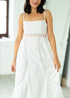 Woman wearing a white dress with intricate detailing in a bright indoor setting