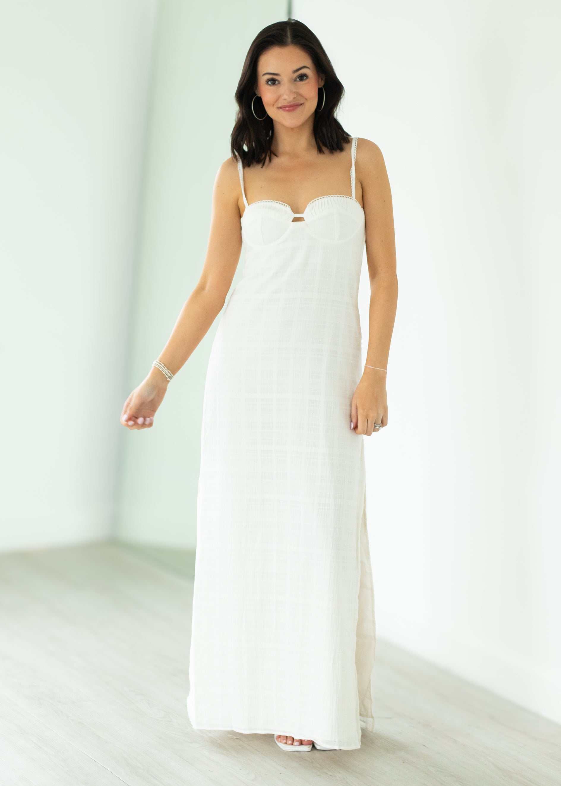 Woman wearing a white strapless dress against a plain background