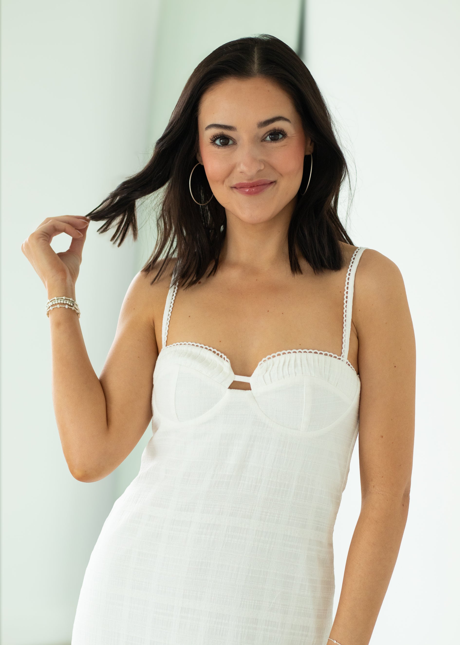 Woman wearing a white dress with thin straps against a light background