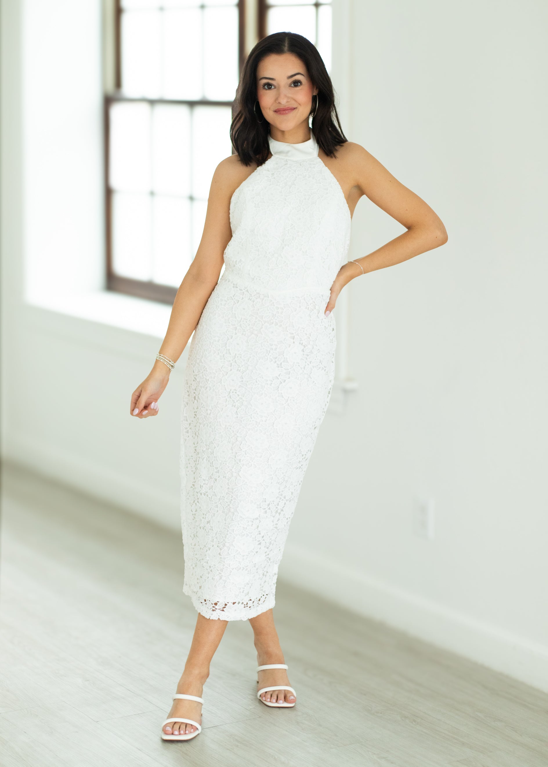 Woman wearing a white lace dress in a bright room