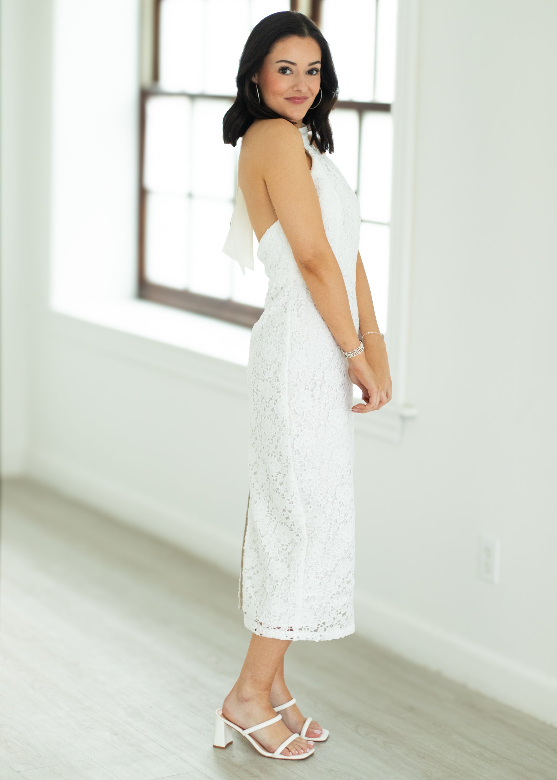 Woman wearing a white lace dress in a bright room