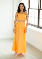 Woman wearing a bright orange outfit in a minimal indoor setting