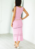 Woman wearing a pink dress with cut-out details on a white background