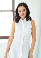 Woman wearing a long white dress against a beige background


