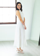 Woman wearing a long white dress against a beige background

