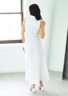 Woman wearing a long white dress against a beige background

