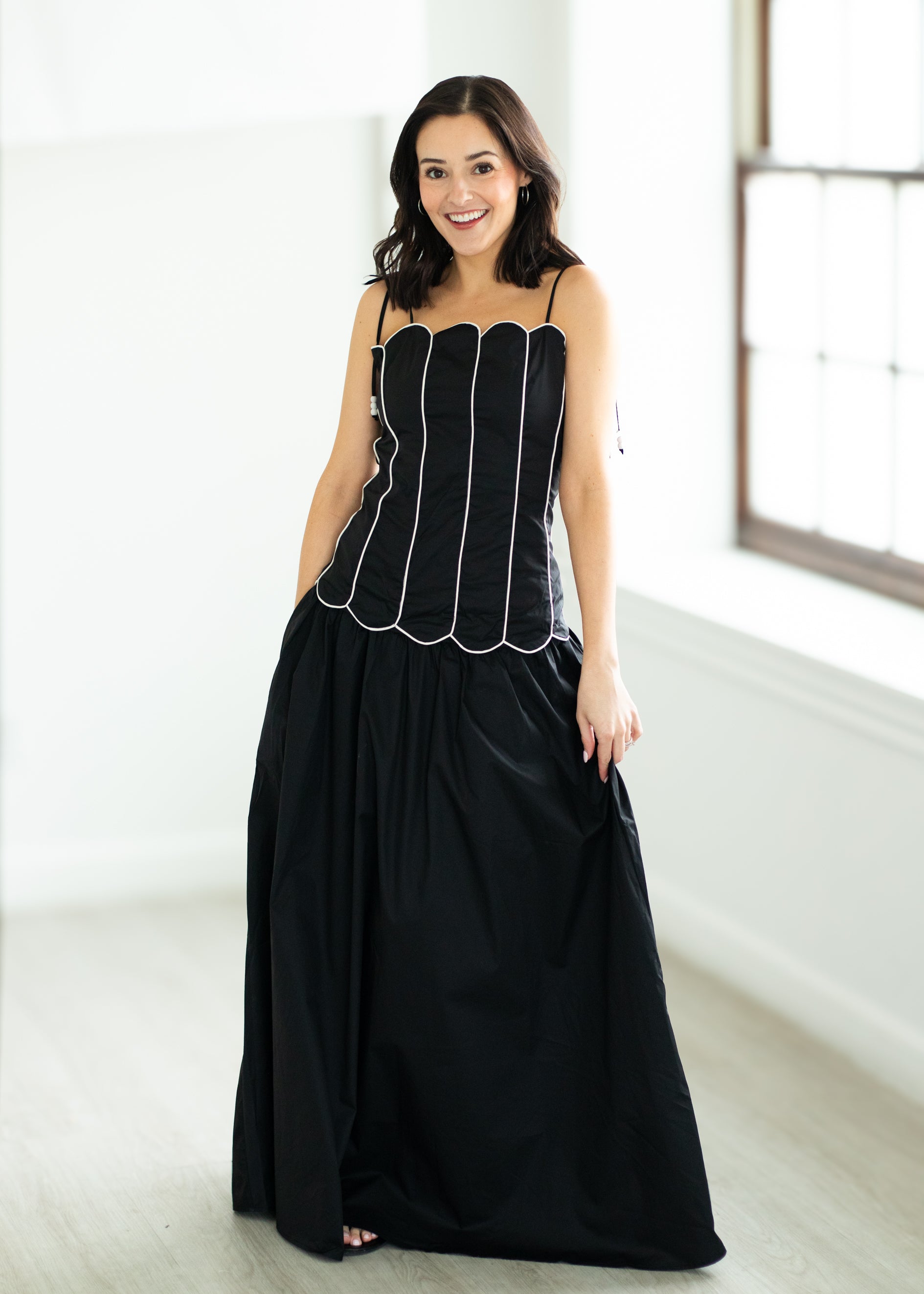 Woman wearing a black set with white trim on a beige background
