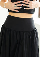 Woman wearing a black set with white trim on a beige background
