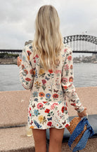 Person wearing a floral dress with a bridge and water in the background
