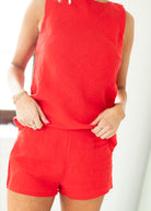 Woman wearing a red sleeveless top and shorts on a white background