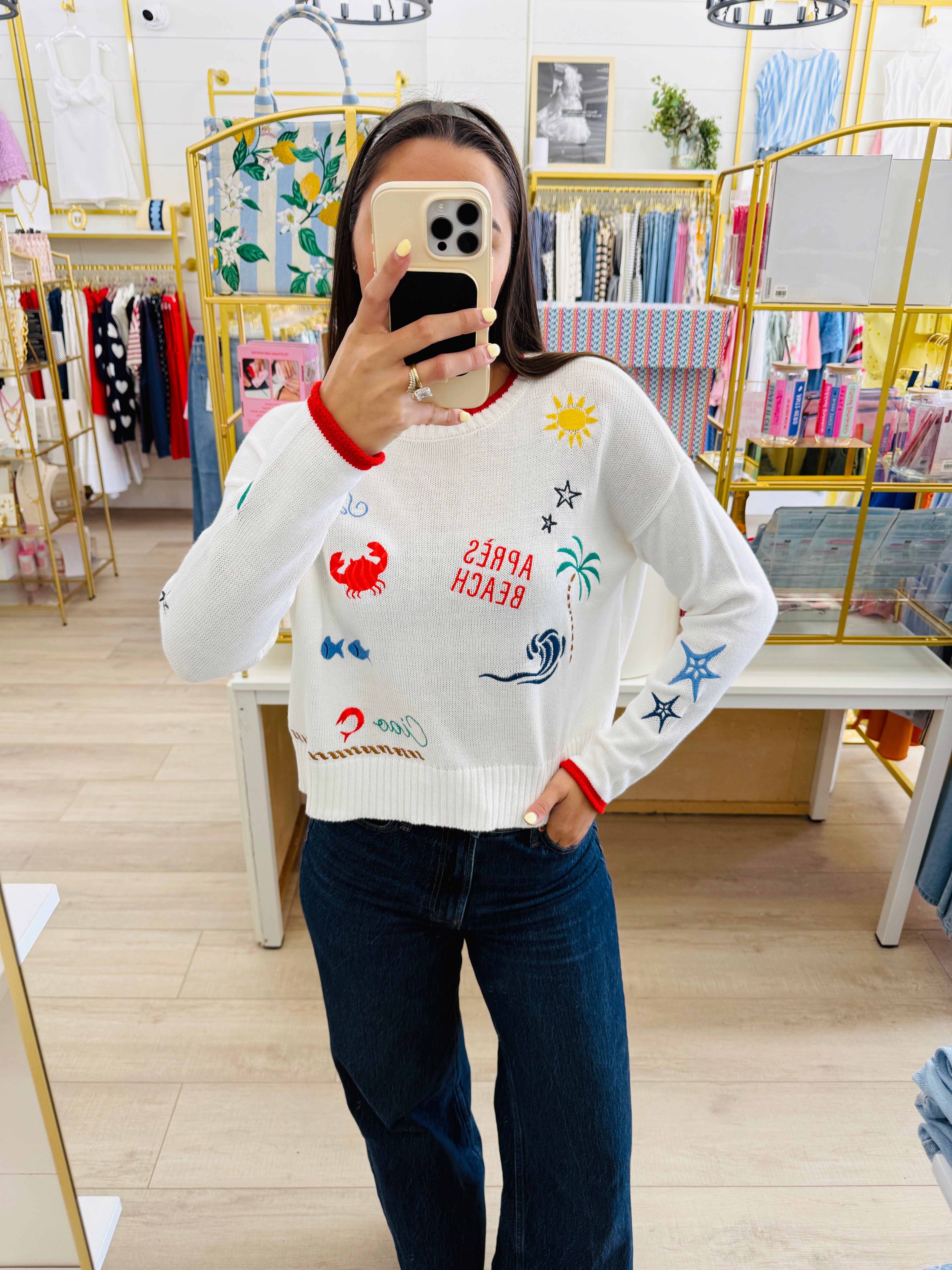 Person wearing a white sweater with colorful designs in a store setting