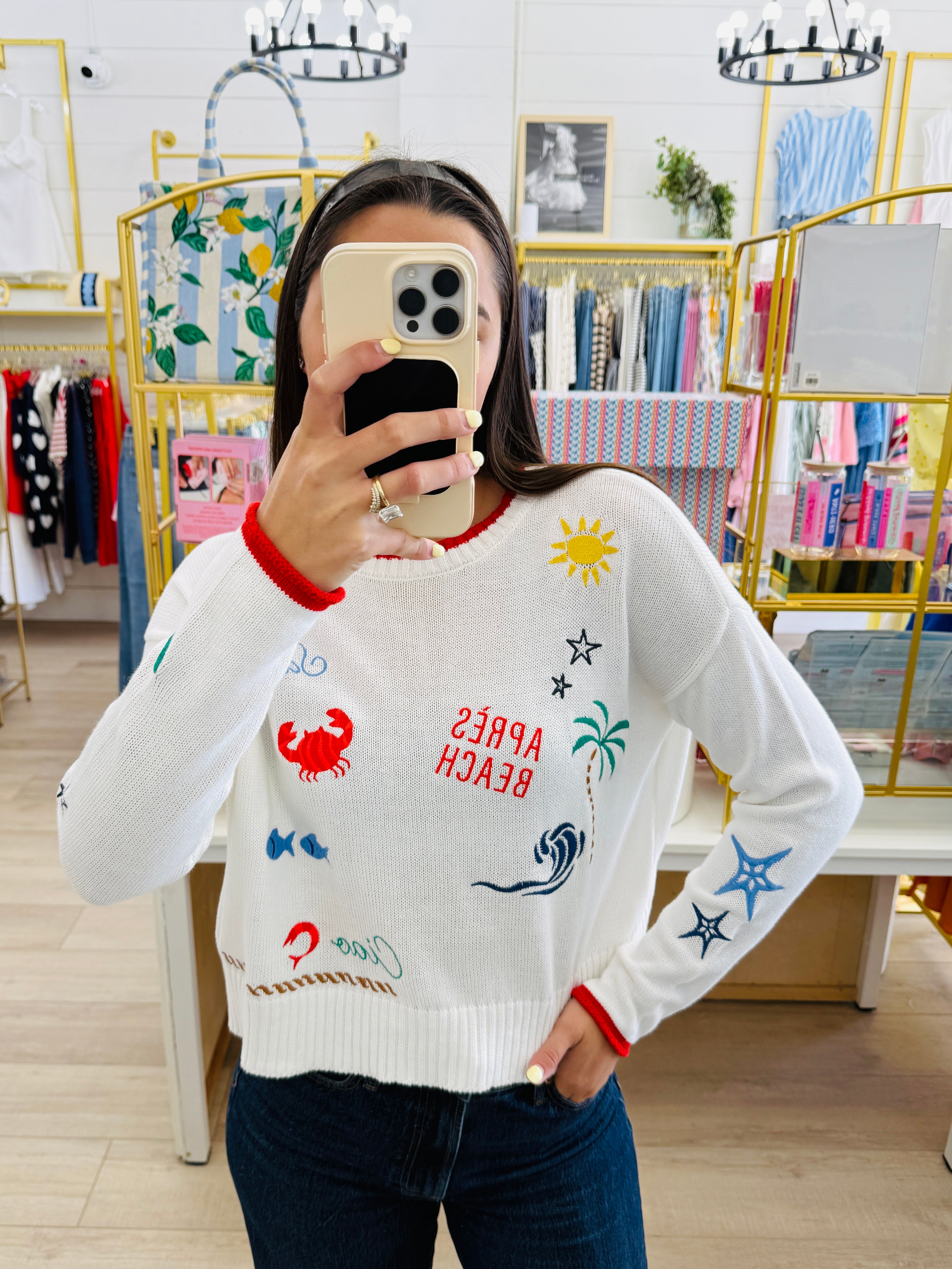 Person wearing a white sweater with colorful graphics in a store setting