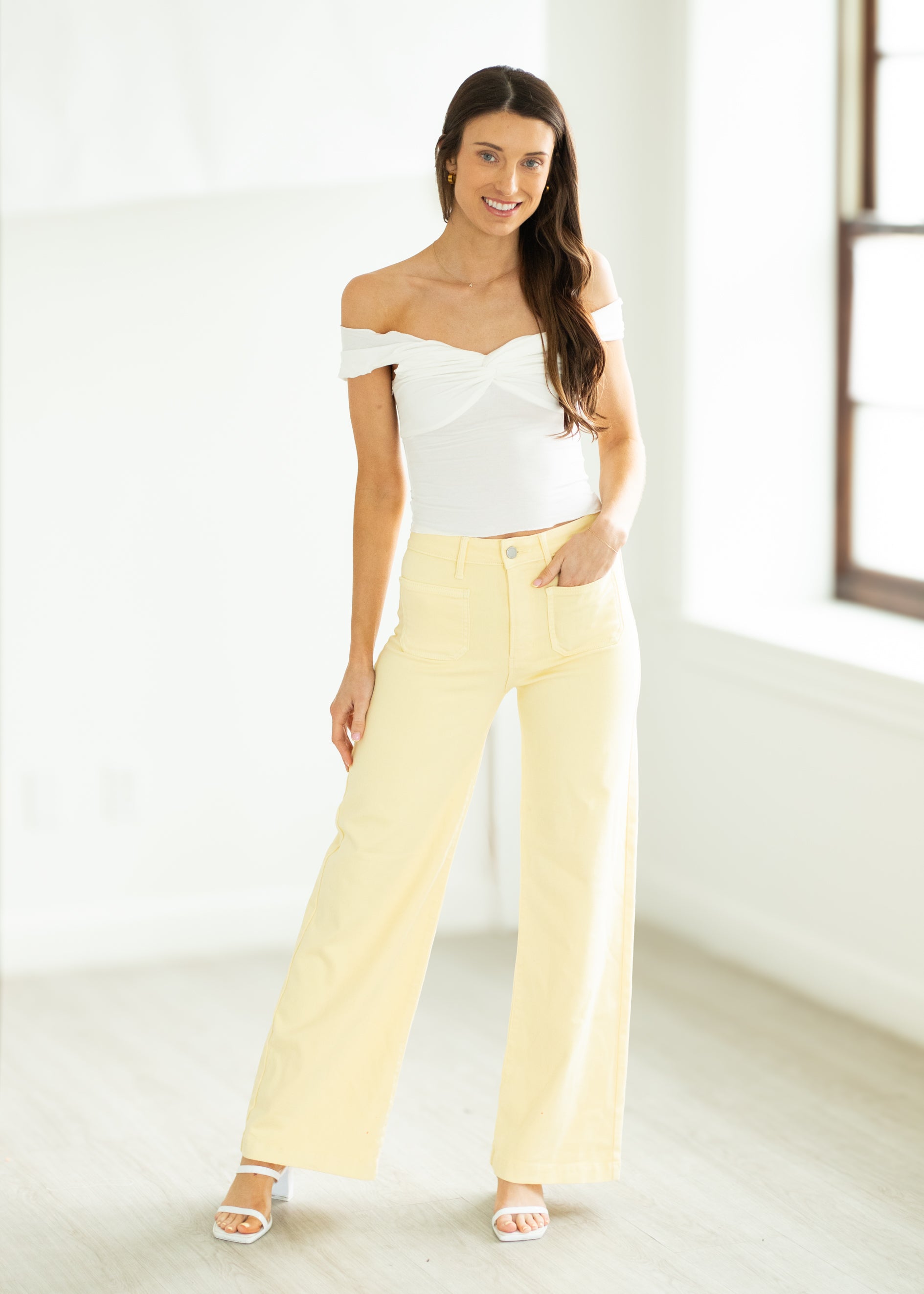 Woman wearing a polka dot top and yellow pants on a white background