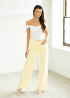 Woman wearing a polka dot top and yellow pants on a white background