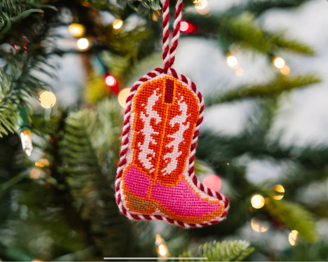 Decorative cowboy boot ornament on a Christmas tree with lights.