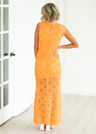 Woman wearing an orange crochet dress against a neutral background

