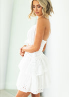 Woman wearing a white dress with cut-out design on a gray background