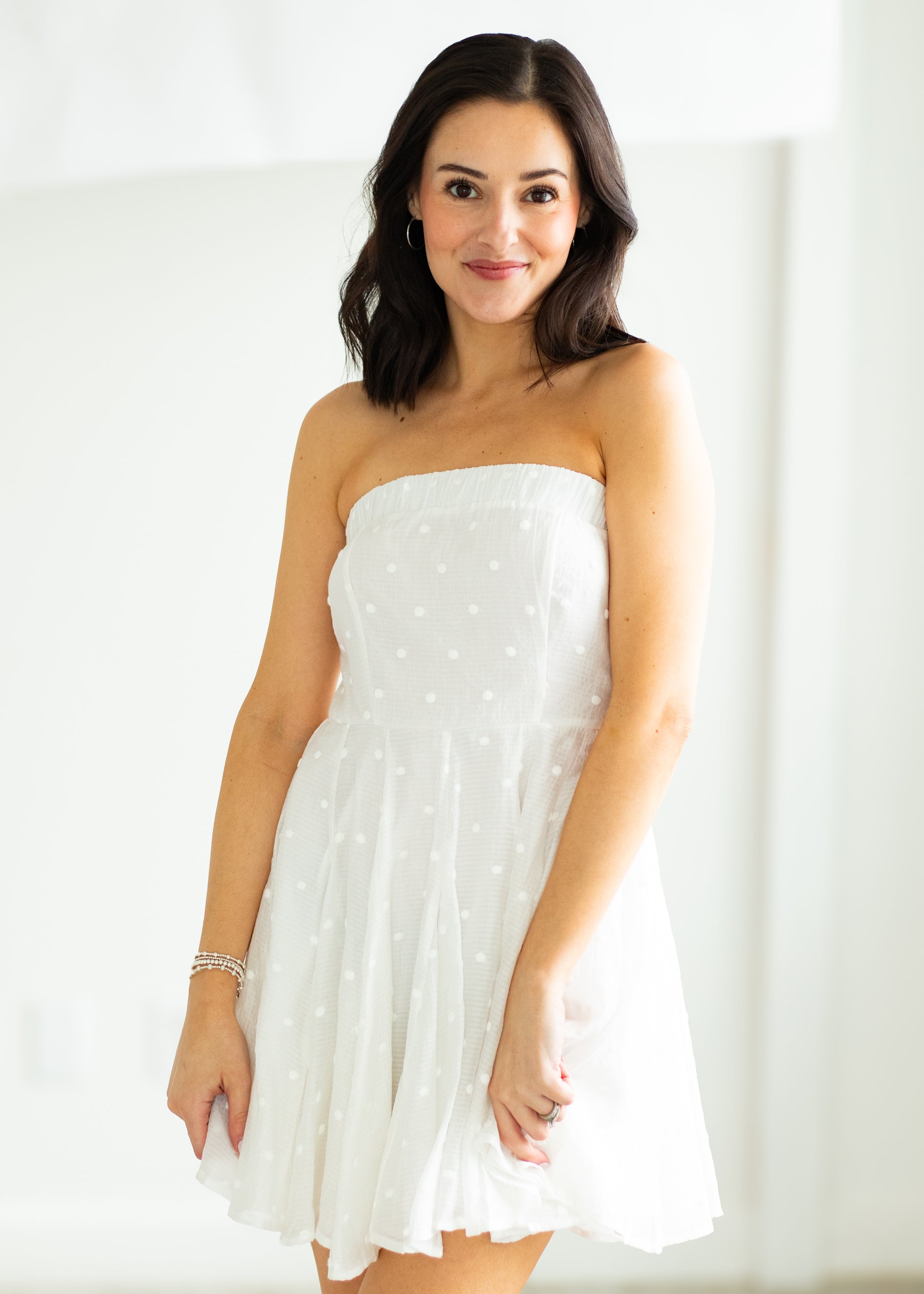 Woman wearing a white strapless dress against a gray background

