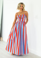 Woman wearing a red and blue striped maxi dress on a white background