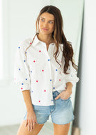 Woman wearing a white blouse with star patterns on a beige background

