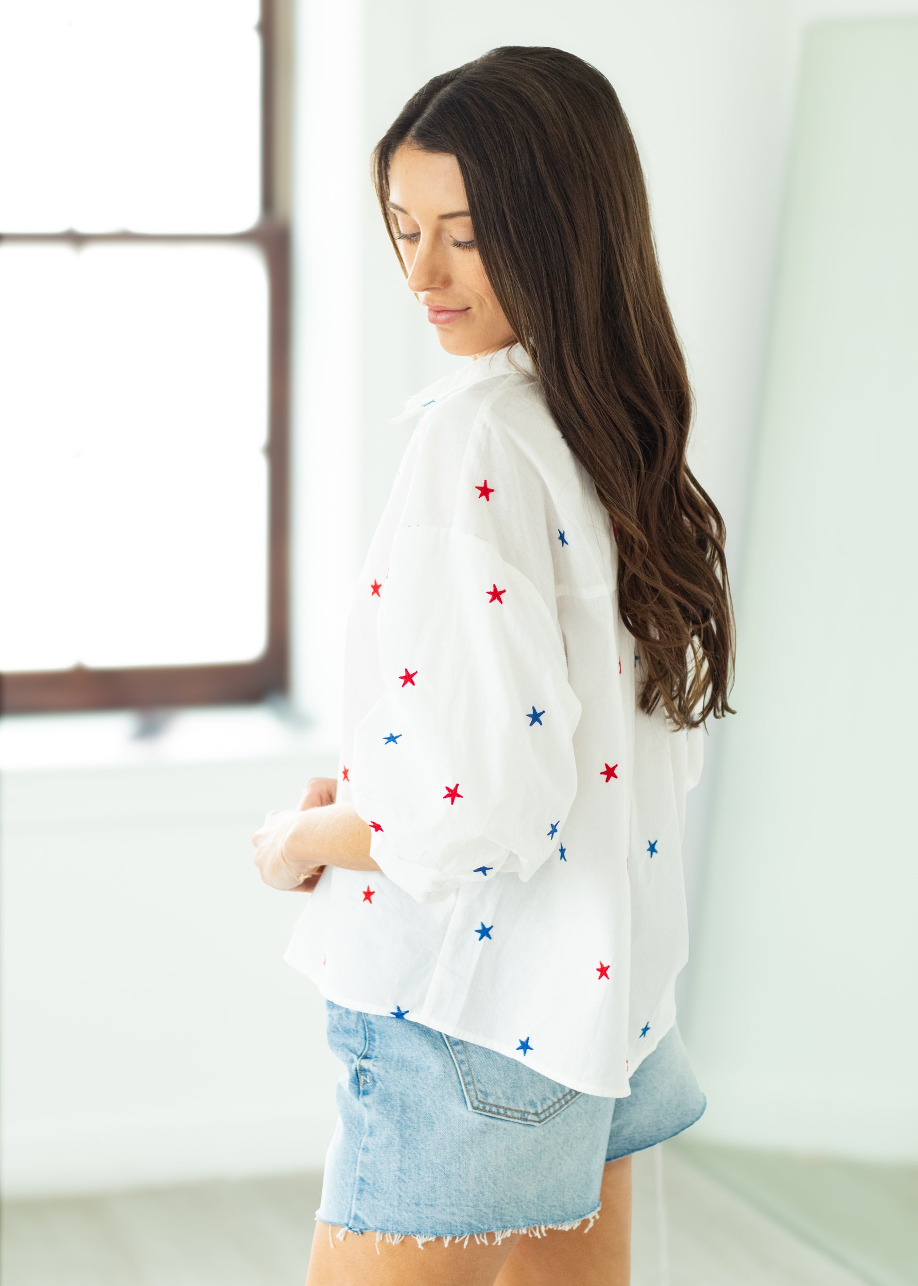 Woman wearing a white blouse with star patterns on a beige background

