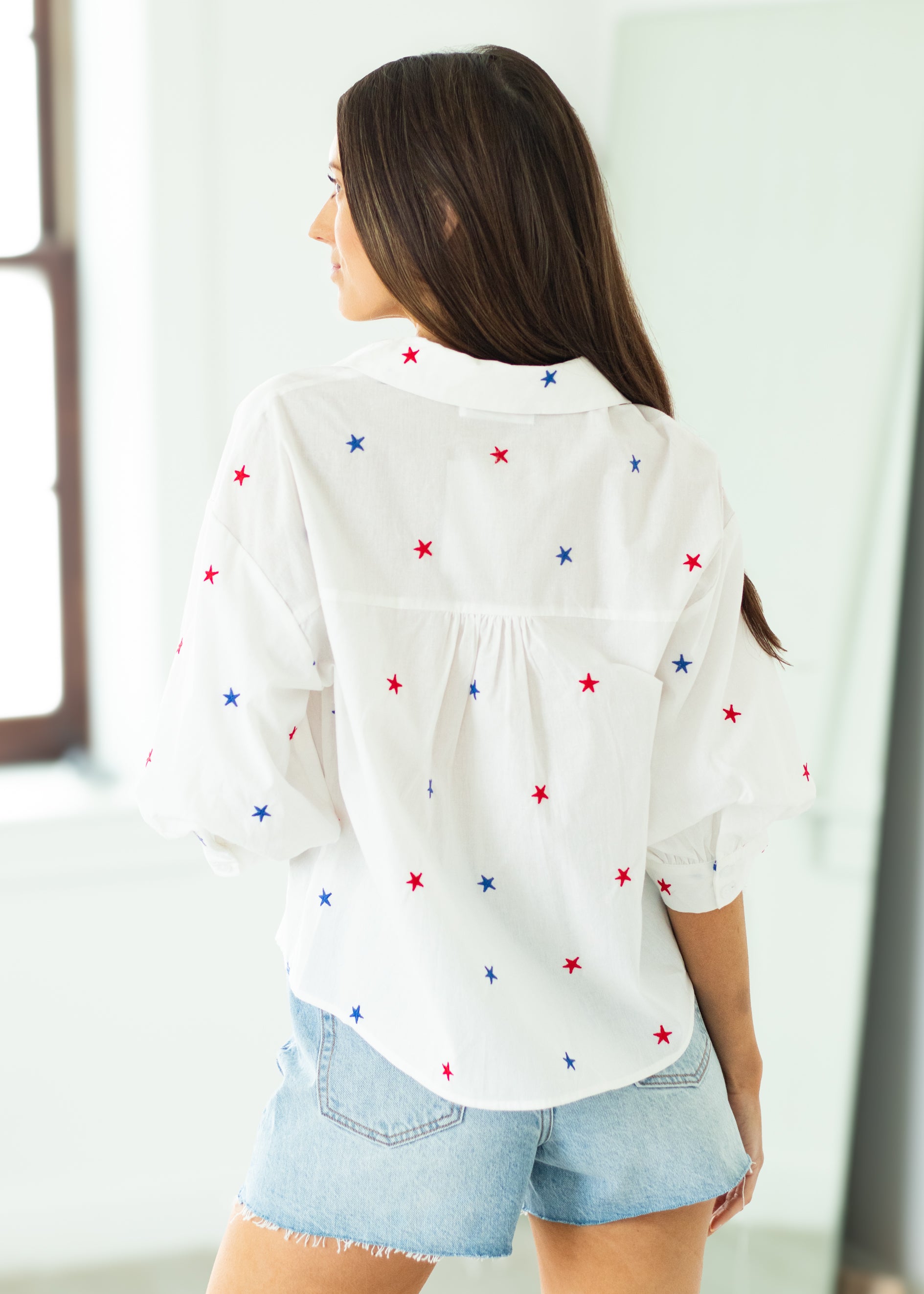 Woman wearing a white blouse with star patterns on a beige background

